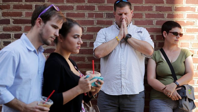 People gather and pray at an informal memorial where 32-year-old Heather Heyer was killed when a car plowed into a crowd of people protesting against the white supremacist 'Unite the Right' rally on Aug. 13, 2017, in Charlottesville, Virginia.
