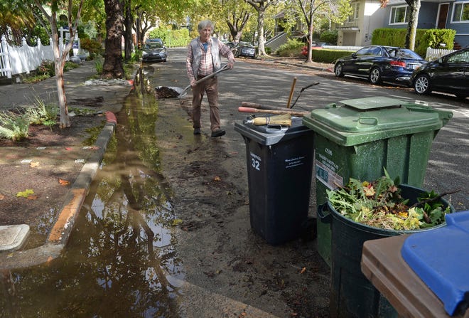 Robert Schmidt cleans up after Saturday's storm in front of his home on C Street in San Rafael, Calif., on Monday, Oct. 25, 2021. During the storm, the street was under water, with several inches of water entering Schmidt's garage.