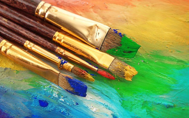 Assorted Paintbrushes on a Textured Multicolor Painted Background