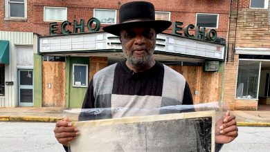 The Rev. David Kennedy stands outside the former Echo Theater, holding a photo of his great-great-uncle's lynching.