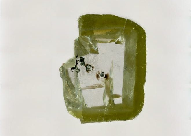 A diamond holds a small piece of the newly unearthed mineral, Davemaoite.