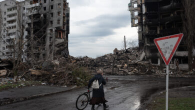 A woman walks near a destroyed apartment building on April 9 in Borodianka, Ukraine.