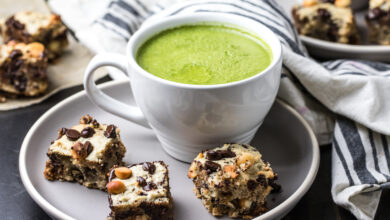 Three macadamia cookie bars on a plate with a mug of Primal Kitchen Matcha Collagen Latte