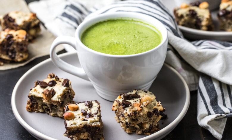 Three macadamia cookie bars on a plate with a mug of Primal Kitchen Matcha Collagen Latte