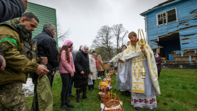 An Orthodox priest sprinkles holy water during the Orthodox Easter service next to The Nativity of the Holy Virgin Church damaged by shelling in the village of Peremoha, Ukraine on April 24.