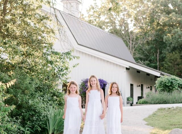 three little girls in white dresses in front of a white church