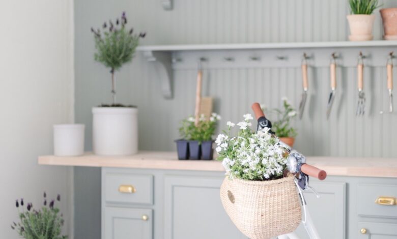 A green built in potting bench with garden tools and flowers, with a white bike in front