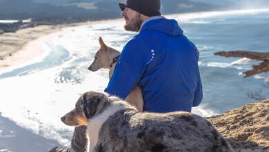 Man in a hat with two dogs enjoying the ocean view along the pet friendly Oregon Coast