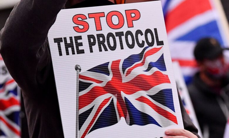 A Loyalist demonstrator holds a sign and a cell phone during a protest against the Northern Ireland protocol as a result of Brexit, in Belfast, Northern Ireland, September 17, 2021. REUTERS/Clodagh Kilcoyne