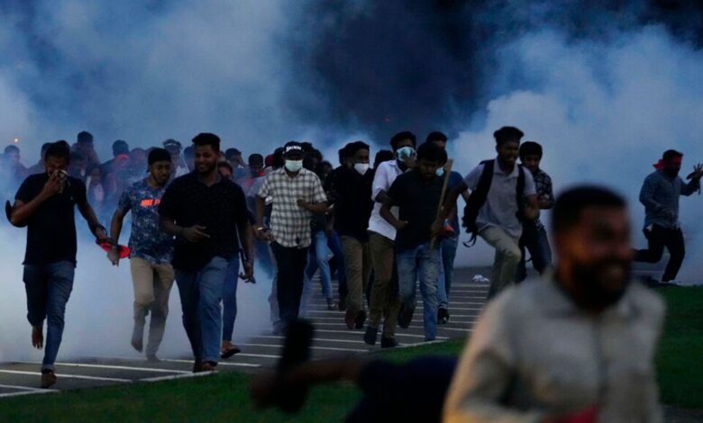 Sri Lanka students run from tear gas during a protest outside parliament in the capital