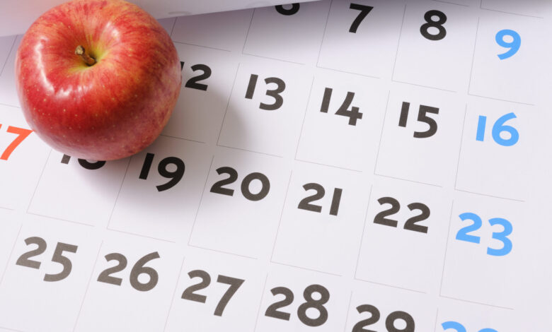 Red apple sitting on calendar.