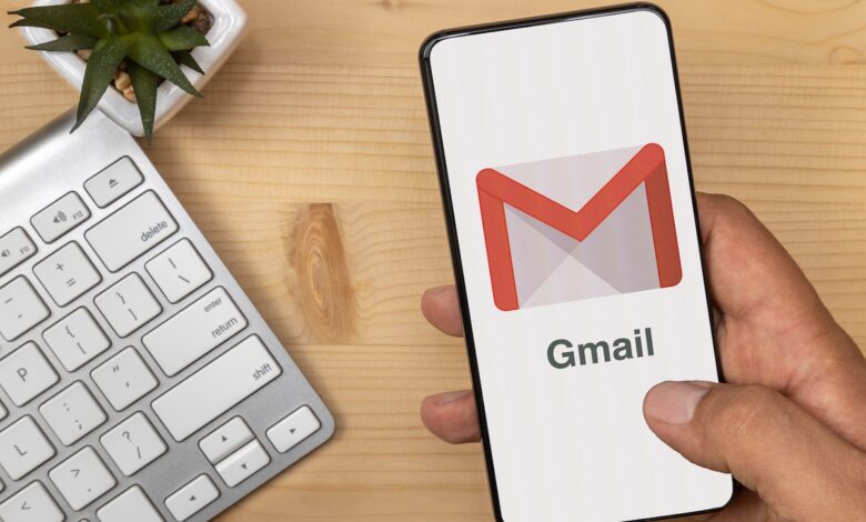 Hand Holding and tapping smartphone with Gmail Logo on it with according text.