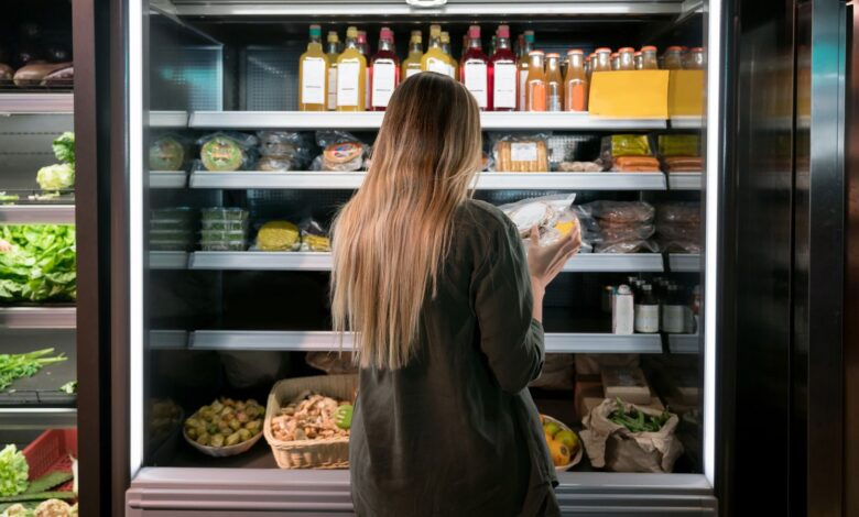 Woman buying food at the supermarket and reading a label on a product - lifestyle concepts