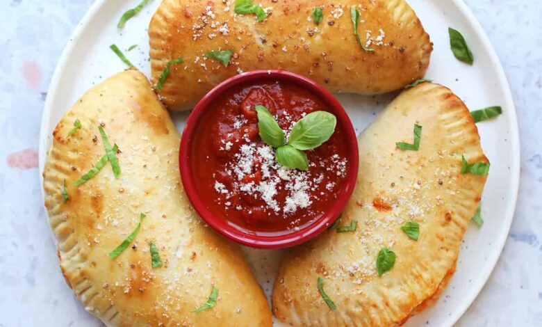 three calzones on a plate with red sauce