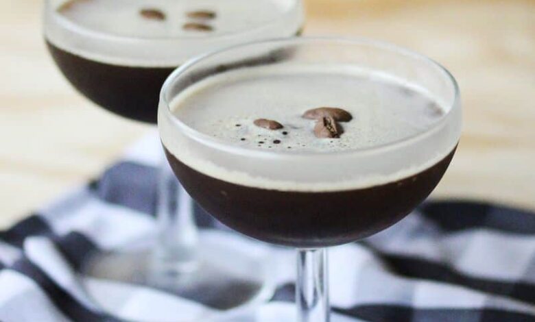 Two espresso martinis ready to be served garnished with coffee beans.