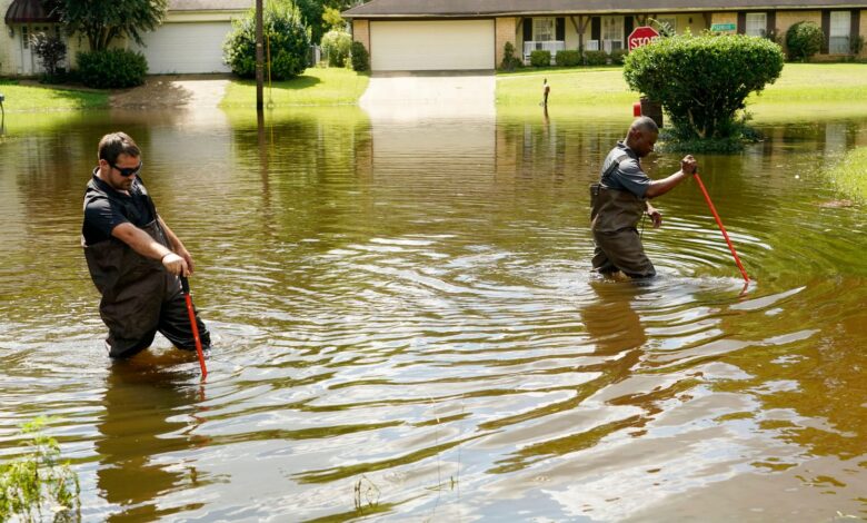 Hinds County Emergency Management Operations deputy director Tracy Funches, right, and operations coordinator Luke Chennault, wade through flood waters in northeast Jackson, Miss., Monday, Aug. 29, 2022, as they check water levels. Flooding affected a number neighborhoods that are near the Pearl River. (AP Photo/Rogelio V. Solis)