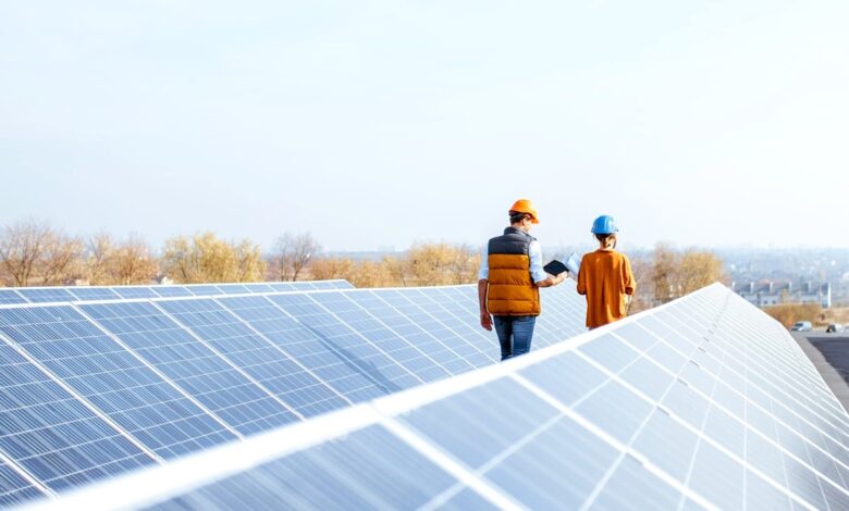 two technicians walking between rows of solar panels