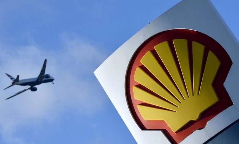 A passenger plane flies over a Shell logo at a petrol station in west London, January 29, 2015. REUTERS/