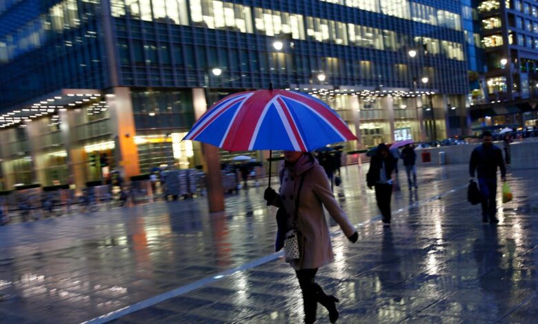Workers walk in the rain at the Canary Wharf business district in London November 11, 2013.