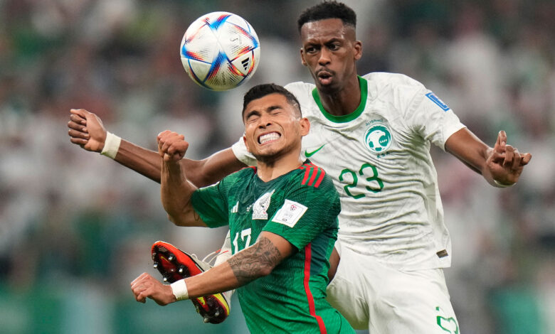 Mexico's Orbelin Pineda, left, and Saudi Arabia's Mohamed Kanno challenge for the ball.