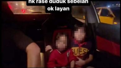 Two kids sit in the front seat of the car in the video as the driver appears to be racing another car