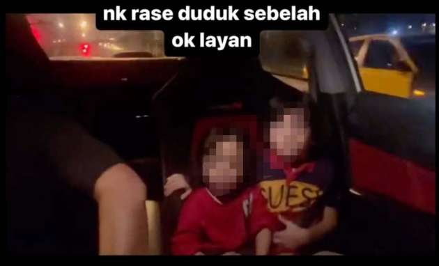 Two kids sit in the front seat of the car in the video as the driver appears to be racing another car