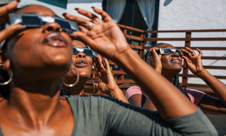 Women friends at home enjoying solar eclipse looking at the sun with eclipse sunglasses