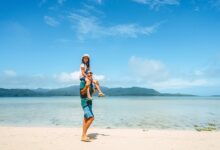 Father carrying young daughter on shoulders on tropical beach
